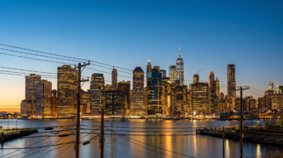 New York skyline at dusk with power lines and city lights.