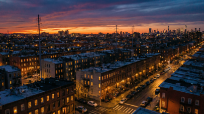 New York City neighborhood at dusk showing energy infrastructure and glowing apartment windows